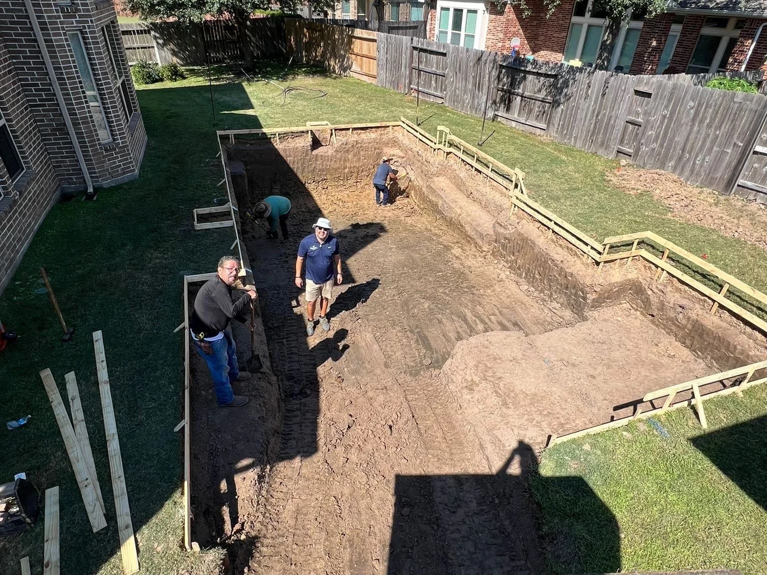 Costa Maya Pools crew standing in a freshly excavated custom pool in a Greater Houston backyard