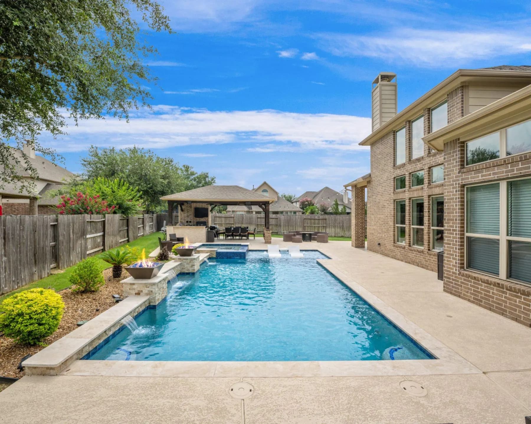 Custom pool with lit fire bowls, water spillovers and a raised spa built by Costa Maya Pools